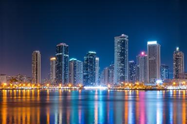 Sharjah Corniche at night with illuminated skyscrapers